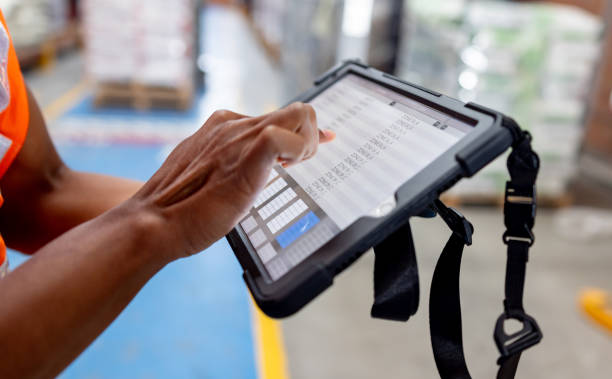 Close-up on a warehouse worker using a digital tablet while taking inventory of the merchandise
