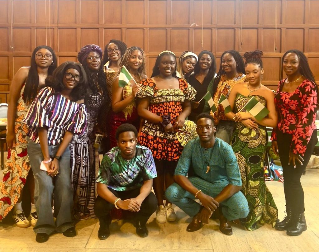 Group of Nigerian students at the University of Toronto wearing colourful clothing and holding Nigerian flags.
